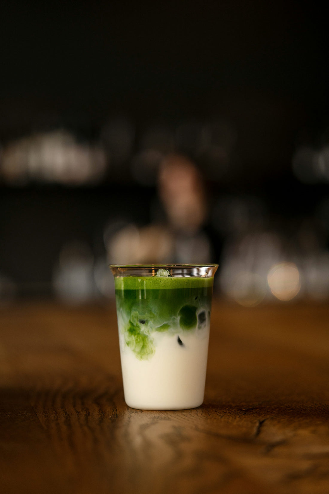 Matcha latte helado sobre una mesa de madera iluminada, momento de pausa durante el día